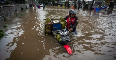 Man pushes his motorbike through water in an area affected by floods following heavy rains in Jakarta, Indonesia, Feb. 20, 2021. (Reuters Photo)