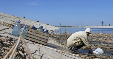 A man scoops water into containers on the bank of a section of the North Crimean Canal outside the town of Krasnoperekopsk, in northern Crimea, May 10, 2014. (Reuters File Photo)