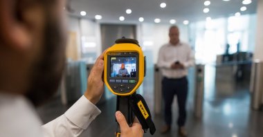 An employee checks the temperature of a returning worker at an office building in London, U.K., June 24, 2020. (Getty Images)