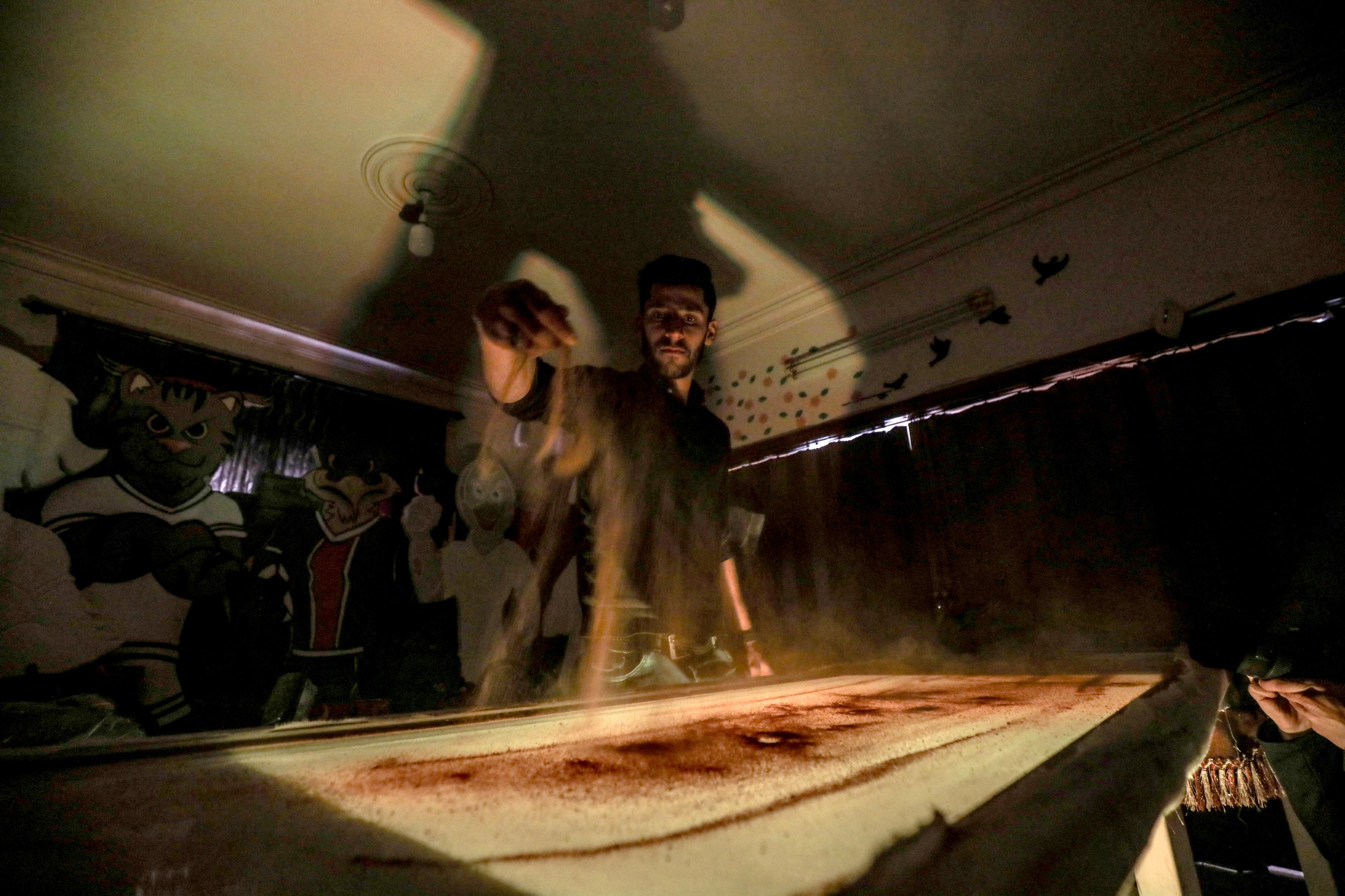 Syrian sand painter Muhammad Said pours sand onto his table, Idlib, Syria, Feb. 22, 2021. (AA Photo)