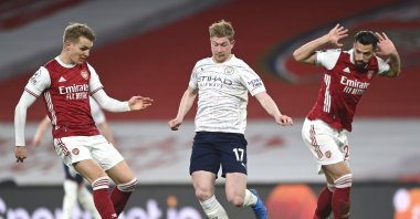 Arsenal's Martin Odegaard (L) and Manchester City's Kevin De Bruyne challenge for the ball during a Premier League match at the Emirates, London, England, Sunday, Feb. 21, 2021. (AP Photo)