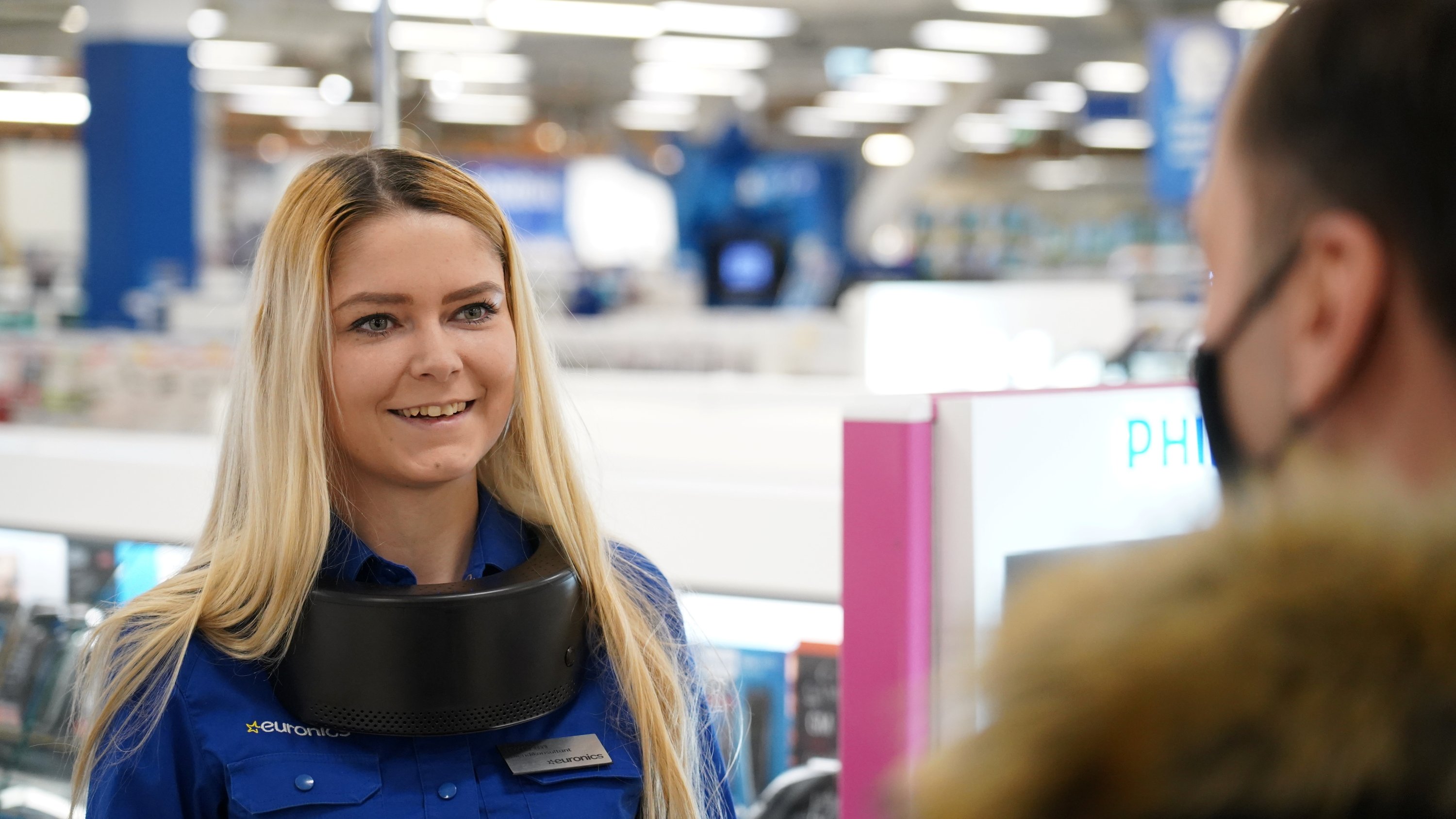 Euronics shop customer service employee Katrin Veltson greets customers while using a wearable UV air purifier to protect against viruses, including COVID-19, in Tallinn, Estonia, Feb. 22, 2021. (Reuters Photo)