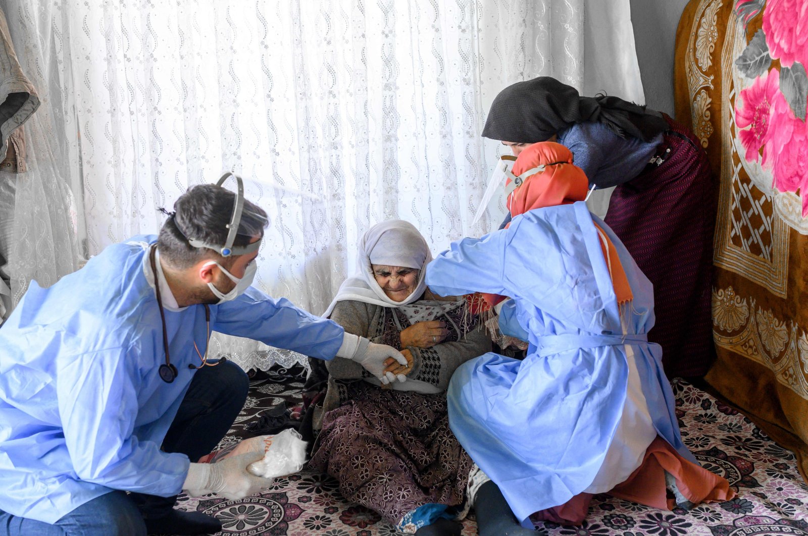 Berfo Arsakay (C), 101 years old, receives a vaccine from nurse Yıldız Ayten (R) from the Bahçesaray public hospital vaccination team as part of an effort to vaccinate residents 65 years old or above against COVID-19, in the village of Güneyyamaç in eastern Turkey, Feb 15, 2021. (AFP Photo)