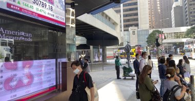 People walk past a bank's electronic board showing the Hong Kong share index in Hong Kong Monday, Feb. 22, 2021. (AP Photo)