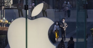 People walk next to the Apple logo in the financial district of Shanghai, China, Feb. 21, 2021. (EPA Photo)