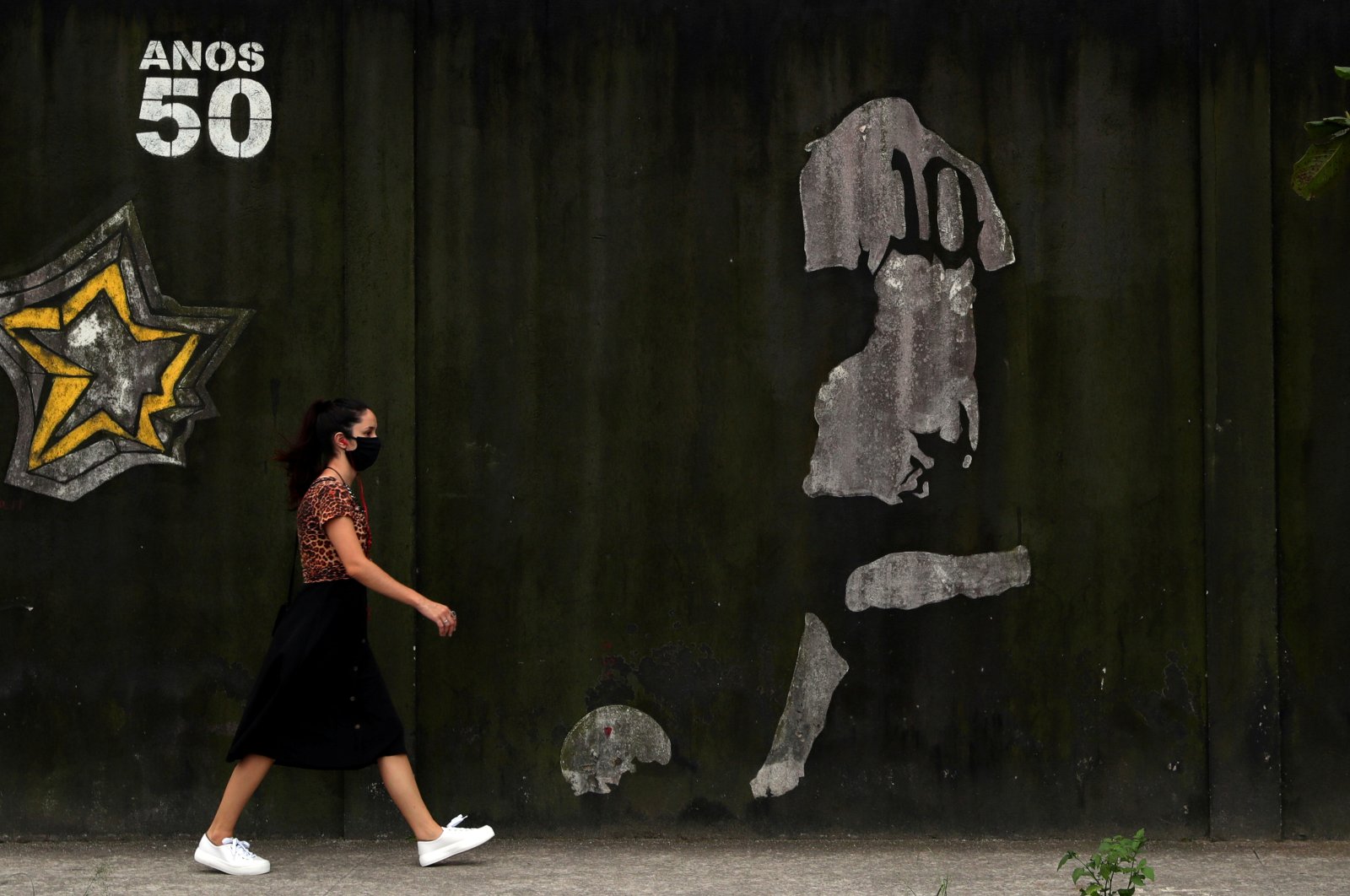 A woman walks by a mural depicting Brazilian soccer legend Pele in his iconic number 10 shirt, in Santos, Brazil, Oct. 20, 2020. (Reuters Photo)