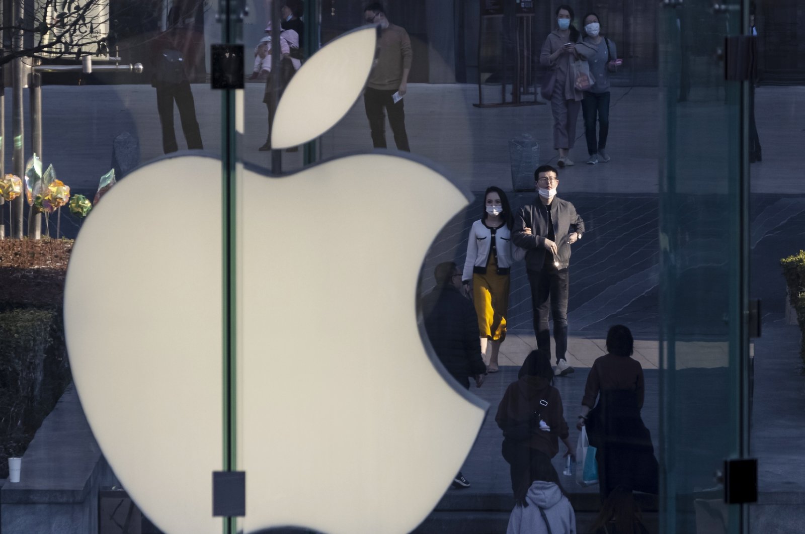 People walk next to the Apple logo in the financial district of Shanghai, China, Feb. 21, 2021. (EPA Photo)