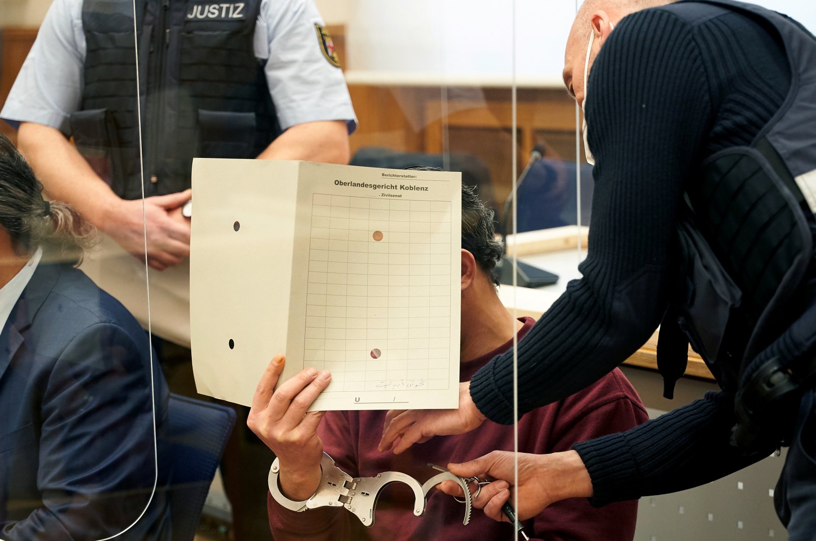Staff removes handcuffs from Syrian defendant Eyad al-Gharib as he arrives to hear the verdict in the courtroom in Koblenz, Germany on Feb. 24, 2021.  (Reuters Photo)