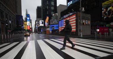 A man crosses the street in a nearly empty Times Square, which is usually very crowded on a weekday morning in New York, March 23, 2020. (AP Photo)