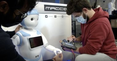 A still image from a video shows Kishhanth Renganathan, Chief Technology Officer (CTO) of Macco Robotics, and another engineer working on a human-like robot in a workshop, Seville, Spain. (AP Photo)