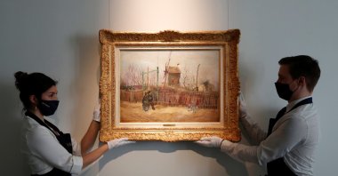 Sotheby's Paris employees pose with the 1887 painting of a Paris street scene "Scene de rue a Montmartre" by the Dutch painter Vincent Van Gogh, France, Feb. 24, 2021. (REUTERS PHOTO)
