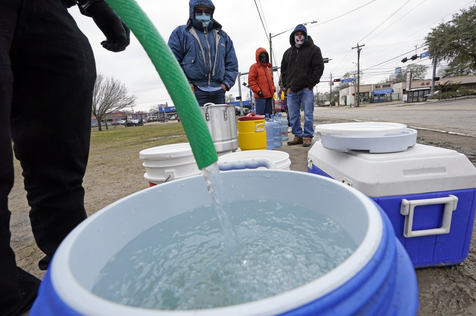 A water bucket is filled as others wait in near-freezing temperatures to use a hose from a public park spigot in Houston, Texas, U.S., Feb. 18, 2021. (AP Photo)