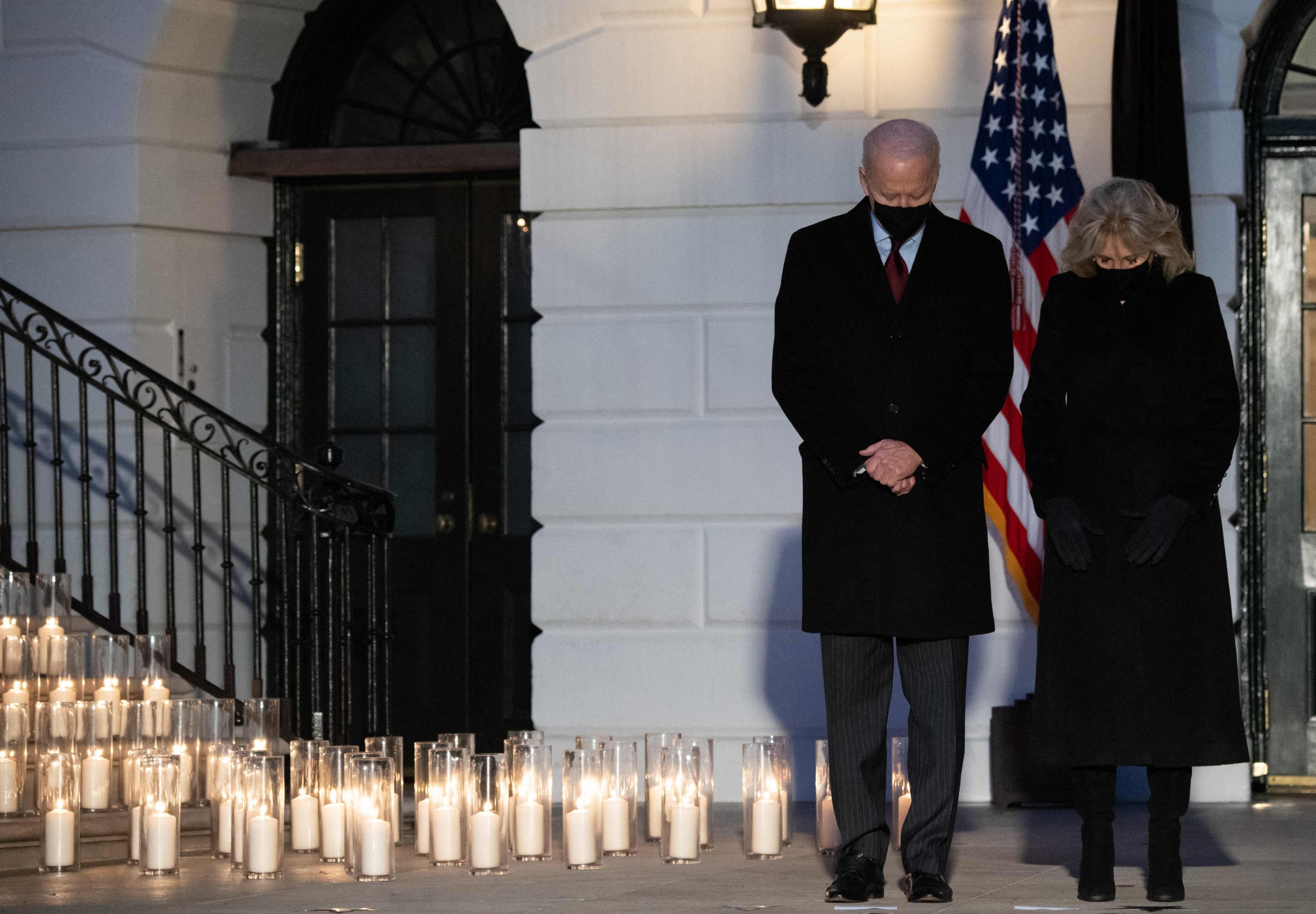 U.S. President Joe Biden (L) and first lady Jill Biden hold a moment of silence during a candlelight ceremony in honor of those who lost their lives to the coronavirus on the South Lawn of the White House in Washington, D.C., Feb. 22, 2021. (Photo by SAUL LOEB / AFP)
