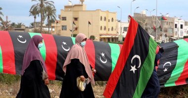 A Libyan woman carries a national flag in the capital Tripoli, Libya, Feb. 25, 2021. (AFP)