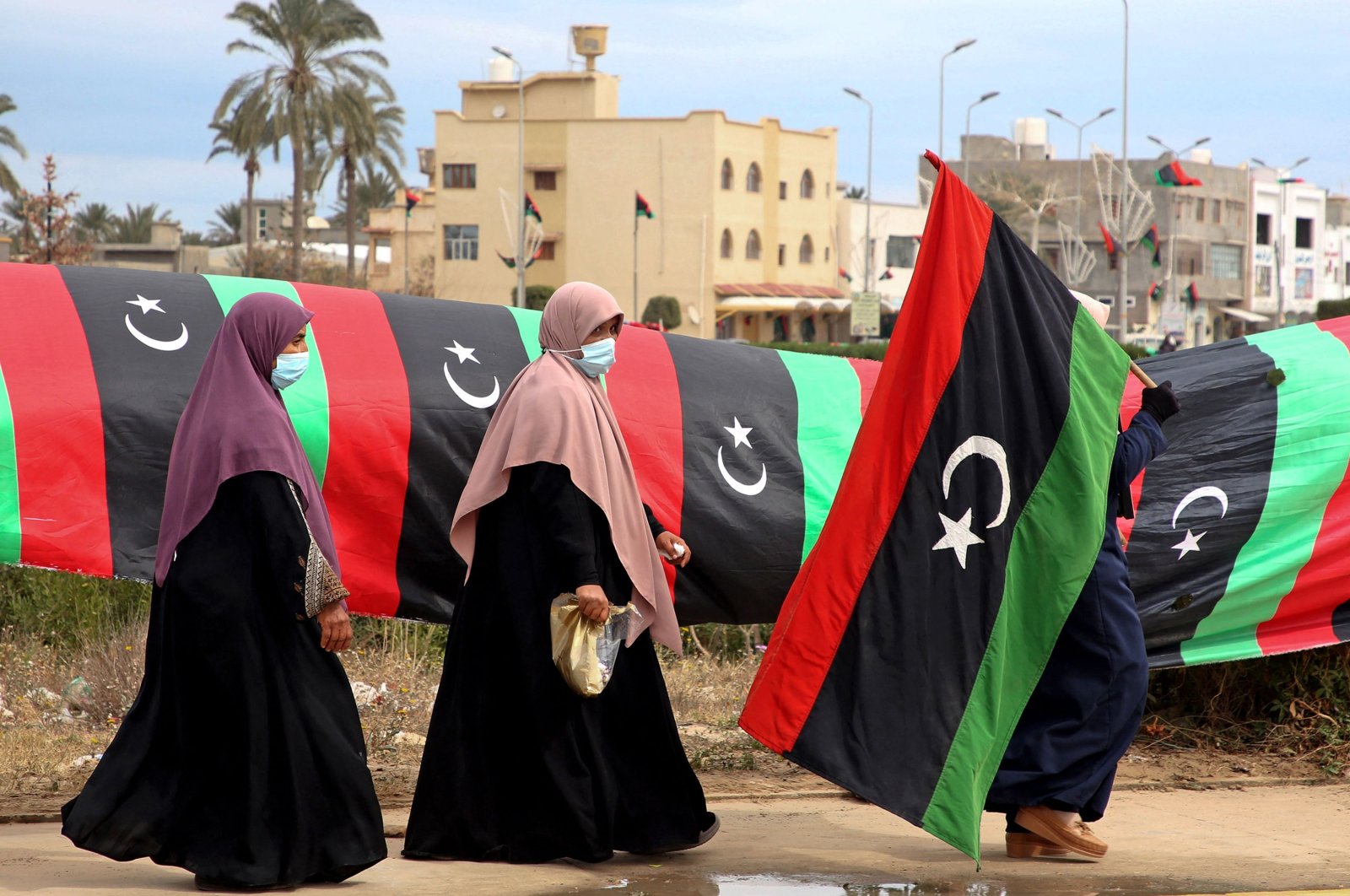 A Libyan woman carries a national flag in the capital Tripoli, Libya, Feb. 25, 2021. (AFP)