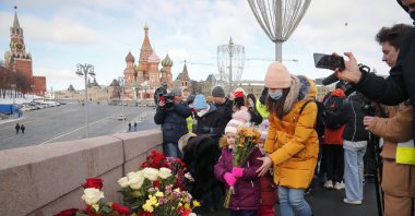 A woman with her children lays flowers near the spot where Russian opposition leader Boris Nemtsov was gunned down, in Moscow, Russia, Feb. 27, 2021. (AP Photo)