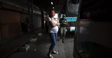 A pregnant woman wearing a protective face mask as a measure to curb the spread of the new coronavirus waits for a bus in Caracas, Venezuela, April 21, 2020. (AP Photo)