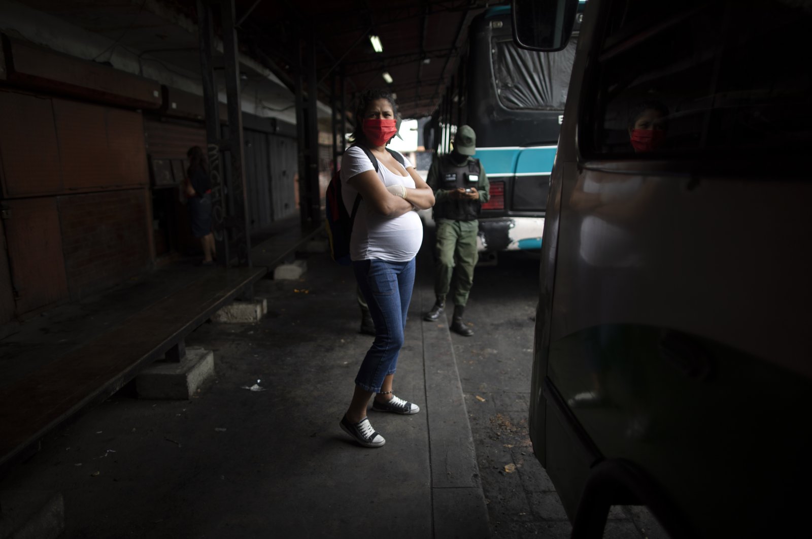 A pregnant woman wearing a protective face mask as a measure to curb the spread of the new coronavirus waits for a bus in Caracas, Venezuela, April 21, 2020. (AP Photo)