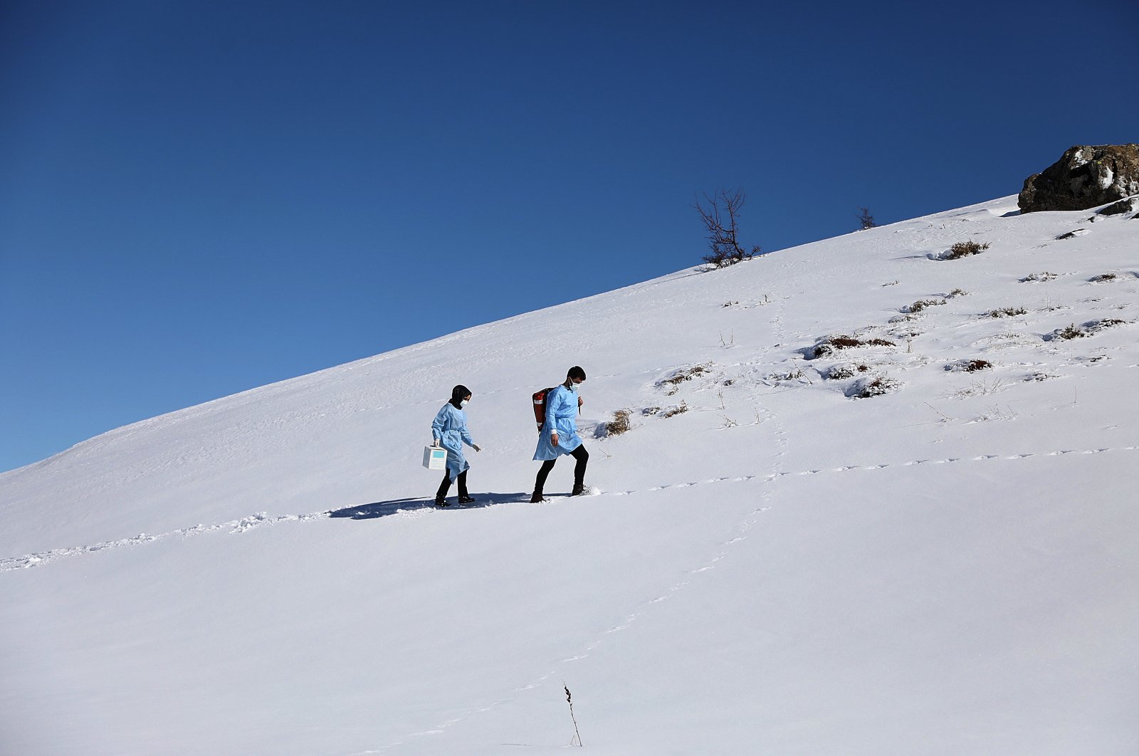 Members of a vaccination crew climb a snowy slope to reach a village in Bingöl, eastern Turkey, Feb. 28, 2021. (AA PHOTO)