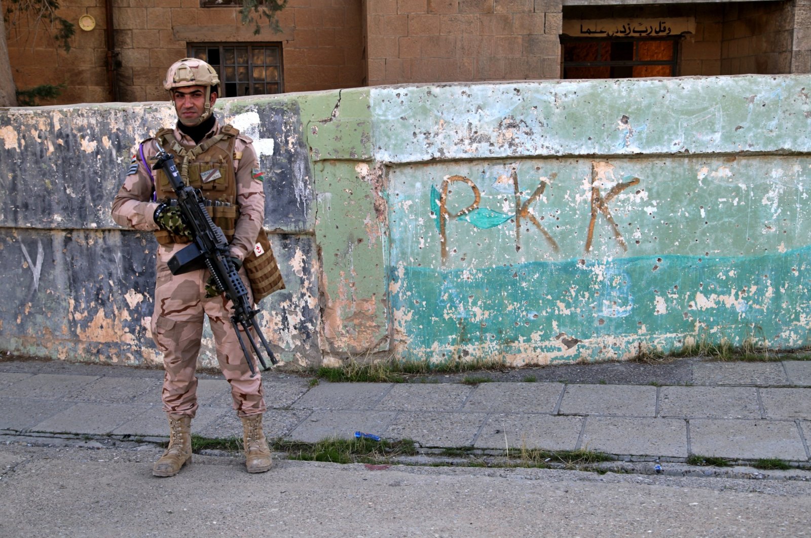 An Iraqi army soldier stands next to graffiti by PKK terrorists who recently withdrew, in Sinjar, Iraq, Dec. 4, 2020. (AP File Photo)