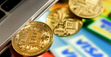 A bitcoin sits in a laptop's CD drive above several credit cards, in Duesseldorf, Germany, Feb. 17, 2021. (EPA Photo)