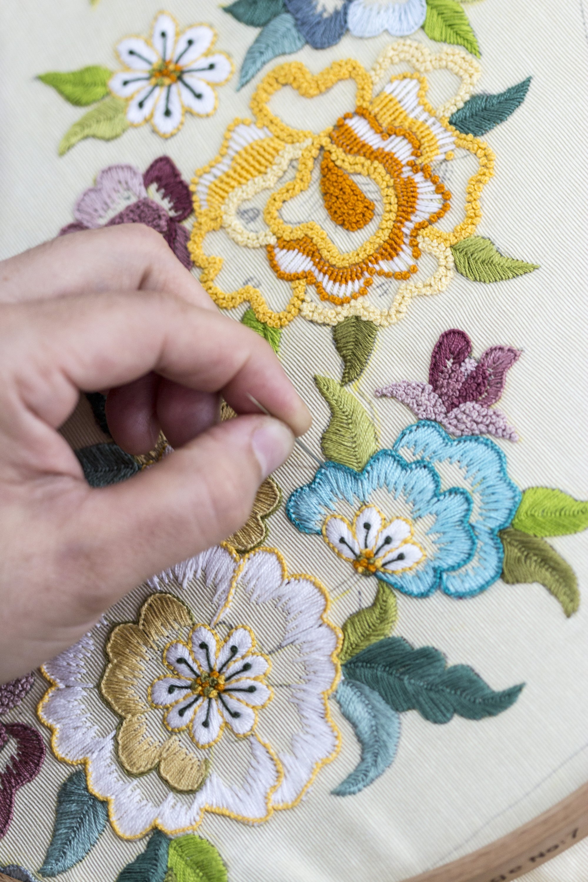 A woman applies Turkish embroidery detailing a floral motif on a piece of fabric. (Shutterstock Photo)