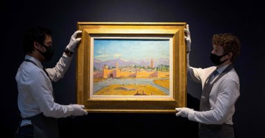 Gallery workers pose with an artwork titled ''Tower of Koutoubia Mosque'' by Winston Churchill during a photocall at Christie's auction house in London, England, Feb. 17, 2021. (AFP Photo)