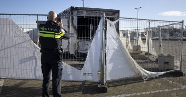 A police officer takes pictures of a destroyed COVID-19 testing facility in the fishing village of Urk in the Netherlands after it was set on fire the night before by rioting youths protesting on the first night of a nationwide curfew, Jan. 24, 2021. (AP Photo)