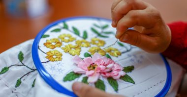 A woman applies Turkish embroidery detailing a floral motif on a piece of fabric. (Shutterstock Photo)