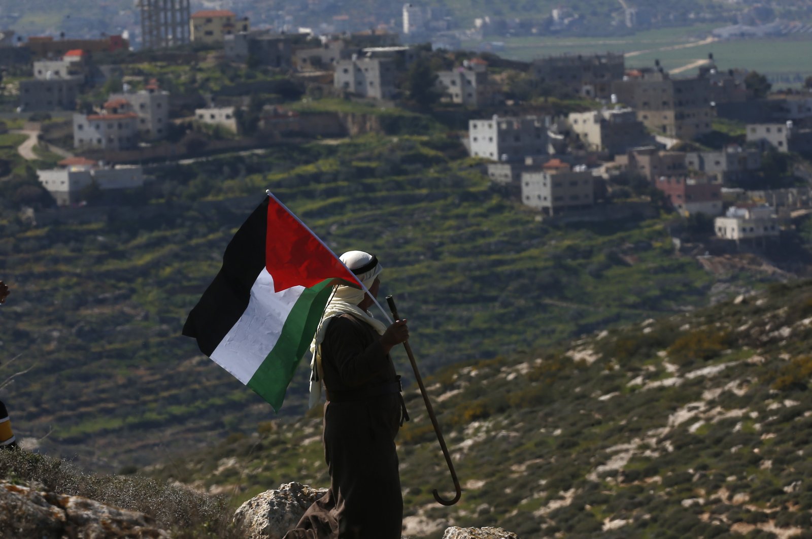 A Palestinian man waves the Palestine flag during a demonstration against Israel's settlements in the village of Bet Dajan near the northern West Bank city of Nablus, Feb. 26, 2021. (EPA File Photo)