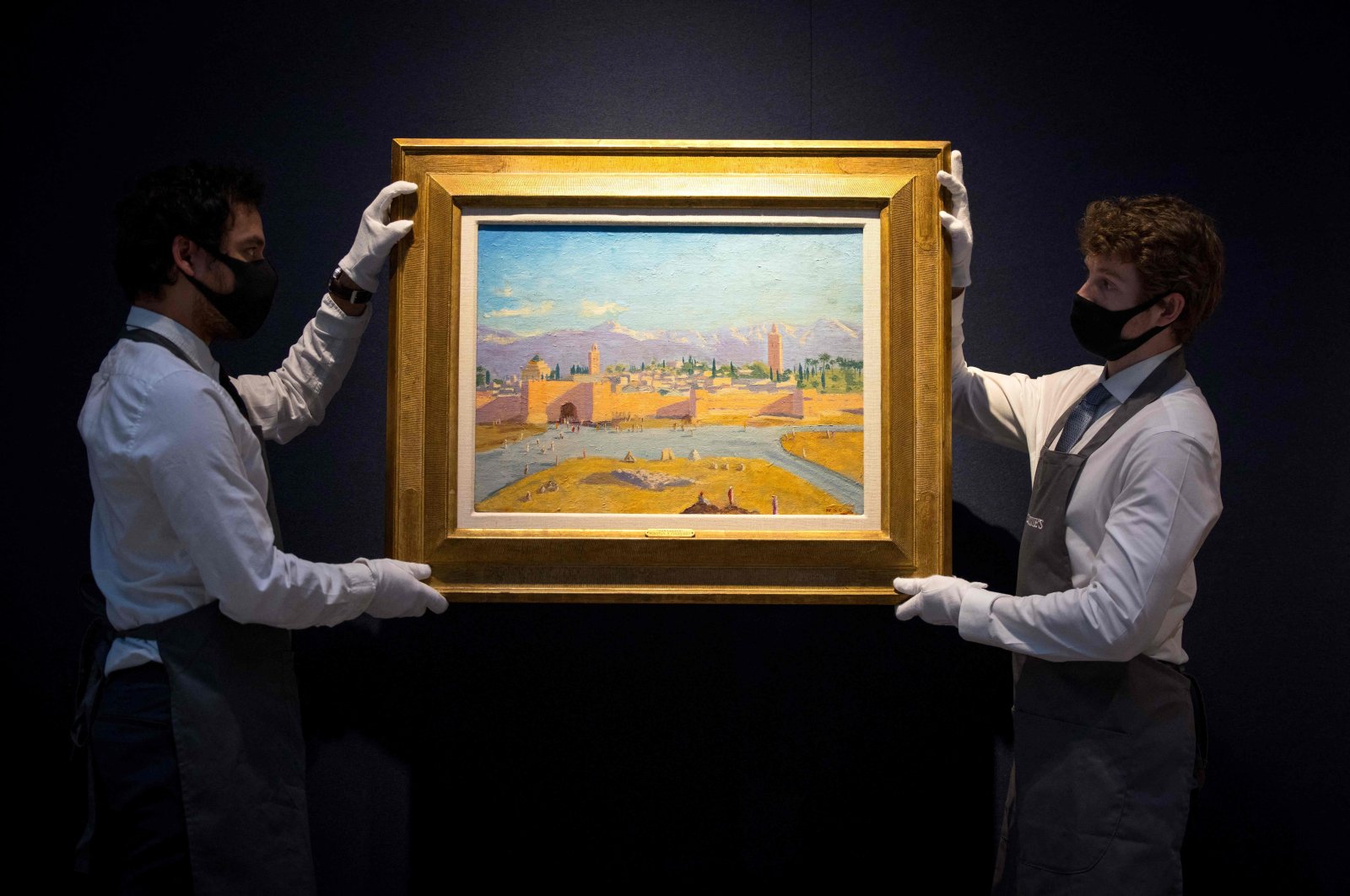 Gallery workers pose with an artwork titled ''Tower of Koutoubia Mosque'' by Winston Churchill during a photocall at Christie's auction house in London, England, Feb. 17, 2021. (AFP Photo)