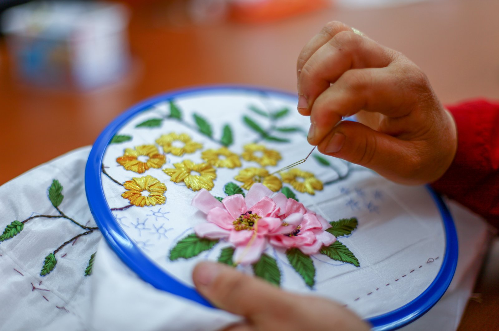 A woman applies Turkish embroidery detailing a floral motif on a piece of fabric. (Shutterstock Photo)