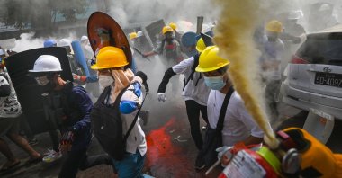 A protester uses a fire extinguisher as others holding homemade shields run during a demonstration against the military coup in Yangon, Myanmar, on March 3, 2021. (AFP Photo)