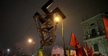 A protester wearing a President Alexander Van der Bellen mask holds a swastika in a basket during a demonstration against the far-right Freedom Party's annual Academics' Ball in Vienna, Austria, Jan. 26, 2018. (Reuters Photo)