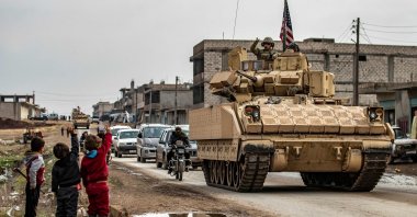 Children greet a U.S. soldier atop a Bradley Fighting Vehicle (BFV) as U.S. troops patrol in the Syrian town of al-Jawadiyah in the northeastern Hassakeh province, Dec. 17, 2020. (AFP Photo)