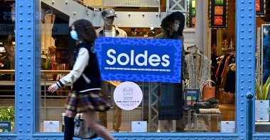 A pedestrian walking past an advertisement indicating discounts in a shop, during the winter sales, in Rennes, northwestern France, Jan. 22, 2021. (AFP Photo)