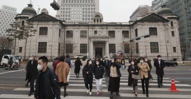 People wearing face masks walk by the headquarters of the Bank of Korea in Seoul, South Korea, March 4, 2021. (AP Photo)
