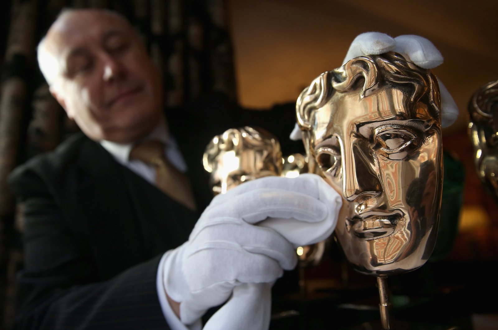 The iconic BAFTA mask awards are polished by a butler at the Savoy Hotel ahead of the British Academy of Film and Television Awards (BAFTA), in London, England, on Feb. 10, 2014. (Getty Images)