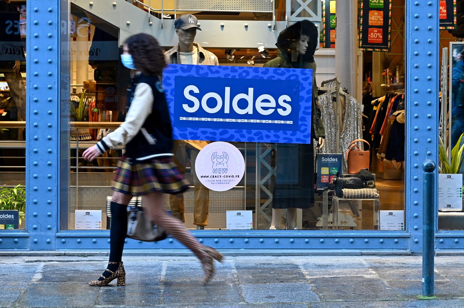 A pedestrian walking past an advertisement indicating discounts in a shop, during the winter sales, in Rennes, northwestern France, Jan. 22, 2021. (AFP Photo)