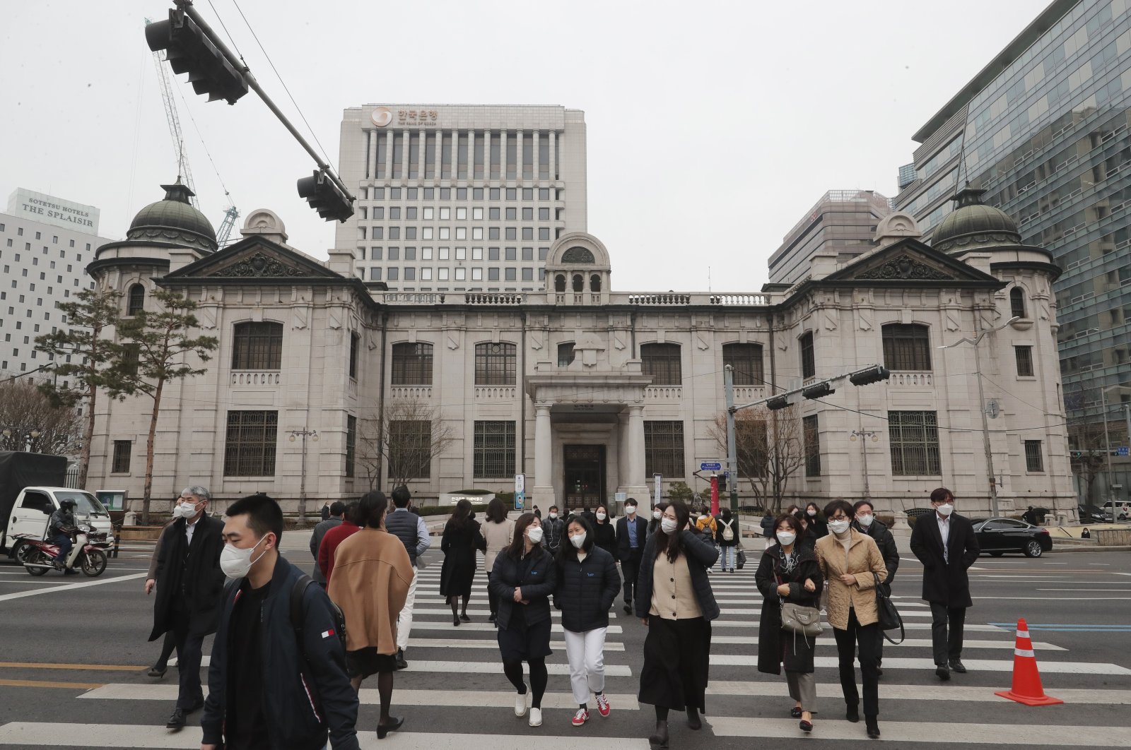 People wearing face masks walk by the headquarters of the Bank of Korea in Seoul, South Korea, March 4, 2021. (AP Photo)