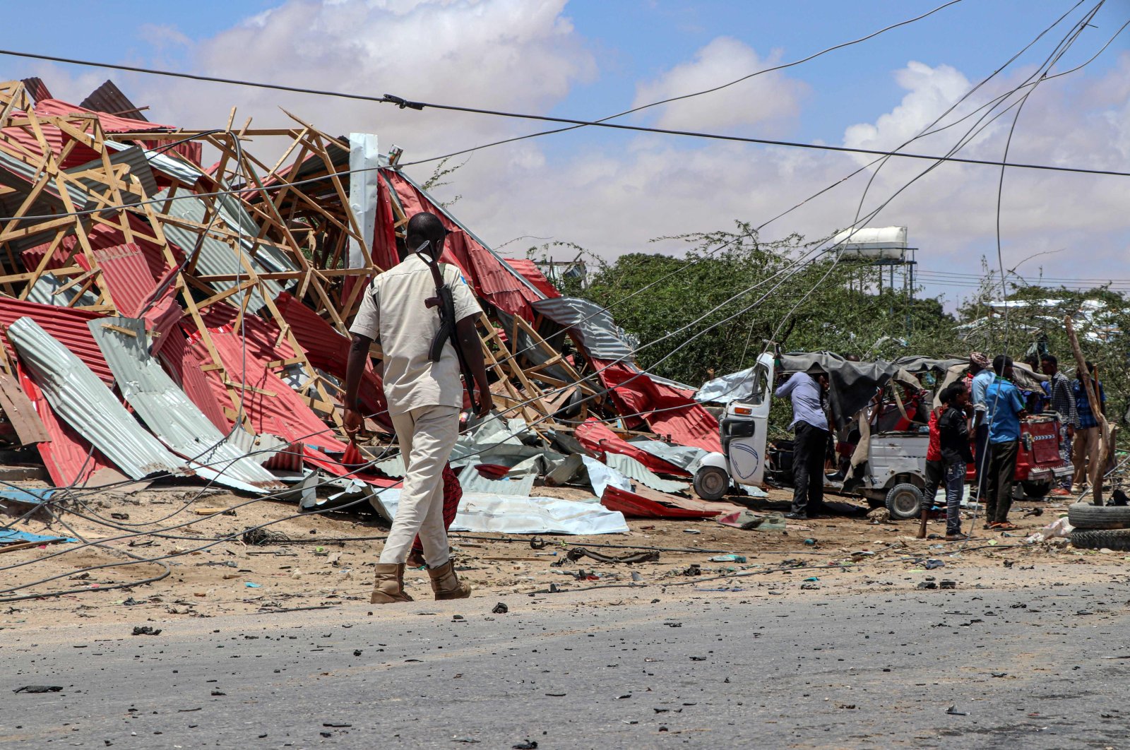 A Somali police officer patrols (L) as bystanders gather at the site of a suicide car bomb explosion that targeted a European Union vehicle convoy in Mogadishu, Somalia, on Sept. 30, 2019. (AFP Photo)