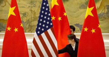 Chinese staffers adjust the U.S. and Chinese flags before the opening session of trade negotiations between U.S. and Chinese trade representatives at the Diaoyutai State Guesthouse in Beijing, Feb. 14, 2019. (AP Photo)