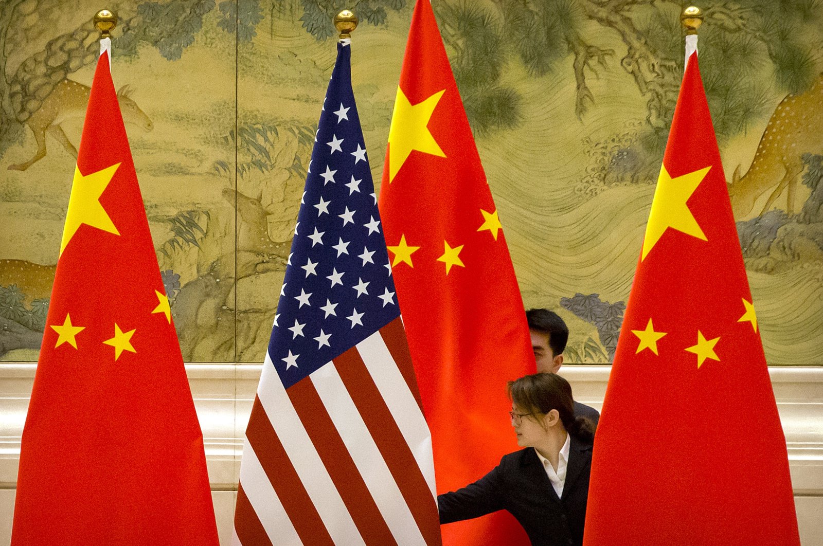 Chinese staffers adjust the U.S. and Chinese flags before the opening session of trade negotiations between U.S. and Chinese trade representatives at the Diaoyutai State Guesthouse in Beijing, Feb. 14, 2019. (AP Photo)