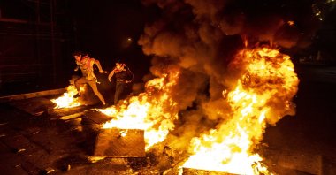 Protesters jump over burning tires that were set on fire to block a road, at Martyrs Square, in downtown Beirut, Lebanon, Saturday, March 6, 2021. (AP Photo)