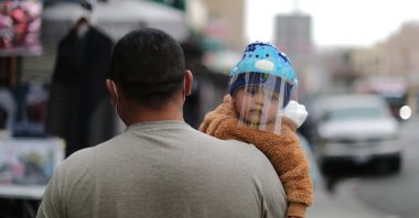 A man carries a baby wearing a face shield as protection against the coronavirus, in Los Angeles, California, U.S., Feb. 10, 2021. (REUTERS Photo)