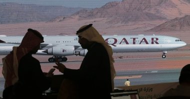 Journalists chat as a video of a plane carrying the Qatari delegation while landing at at Al-Ula airport is shown on a screen, where the 41st Gulf Cooperation Council (GCC) meeting takes place, Saudi Arabia, Jan. 5, 2021. (AP Photo)