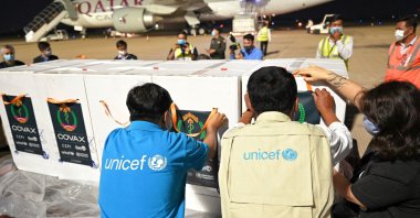 UNICEF staff place stickers on boxes of COVID-19 vaccines during the handover ceremony of the first allocation of Indian-made AstraZeneca vaccine from the Covax facility, at Phnom Penh International Airport on March 2, 2021. (AFP Photo)