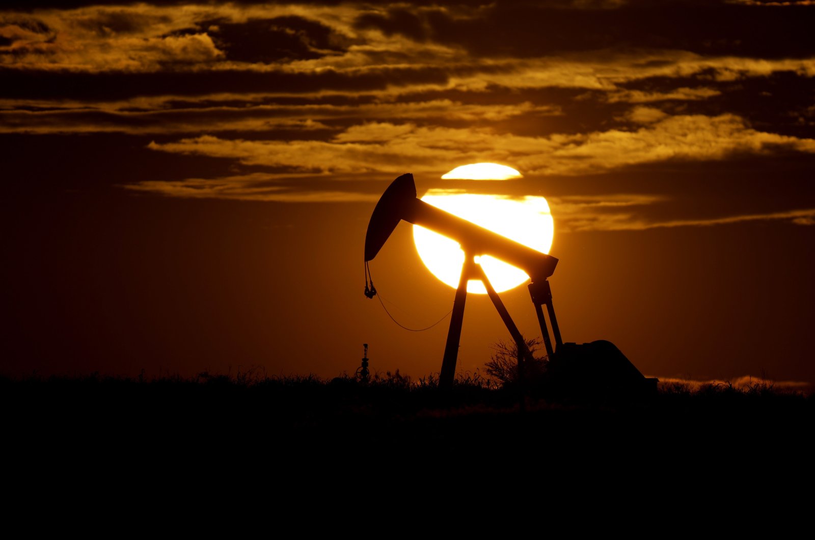 The sun sets behind an idle pump jack near Karnes City, U.S, April 8, 2020. (AP Photo)