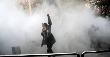 A woman raises his fist amid smoke during an anti-government protest in Iran. (Archive Photo)