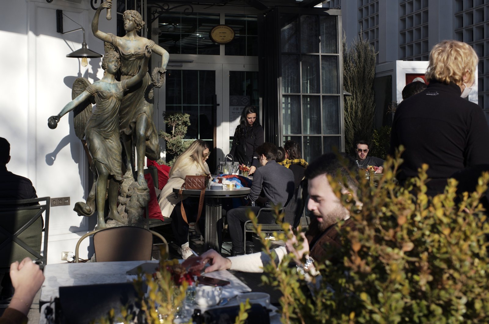 People sit outside a coffee shop as cafes, restaurants and other eateries reopened in some provinces across the country, in the capital Ankara, Turkey, March 3, 2021. (AP Photo)